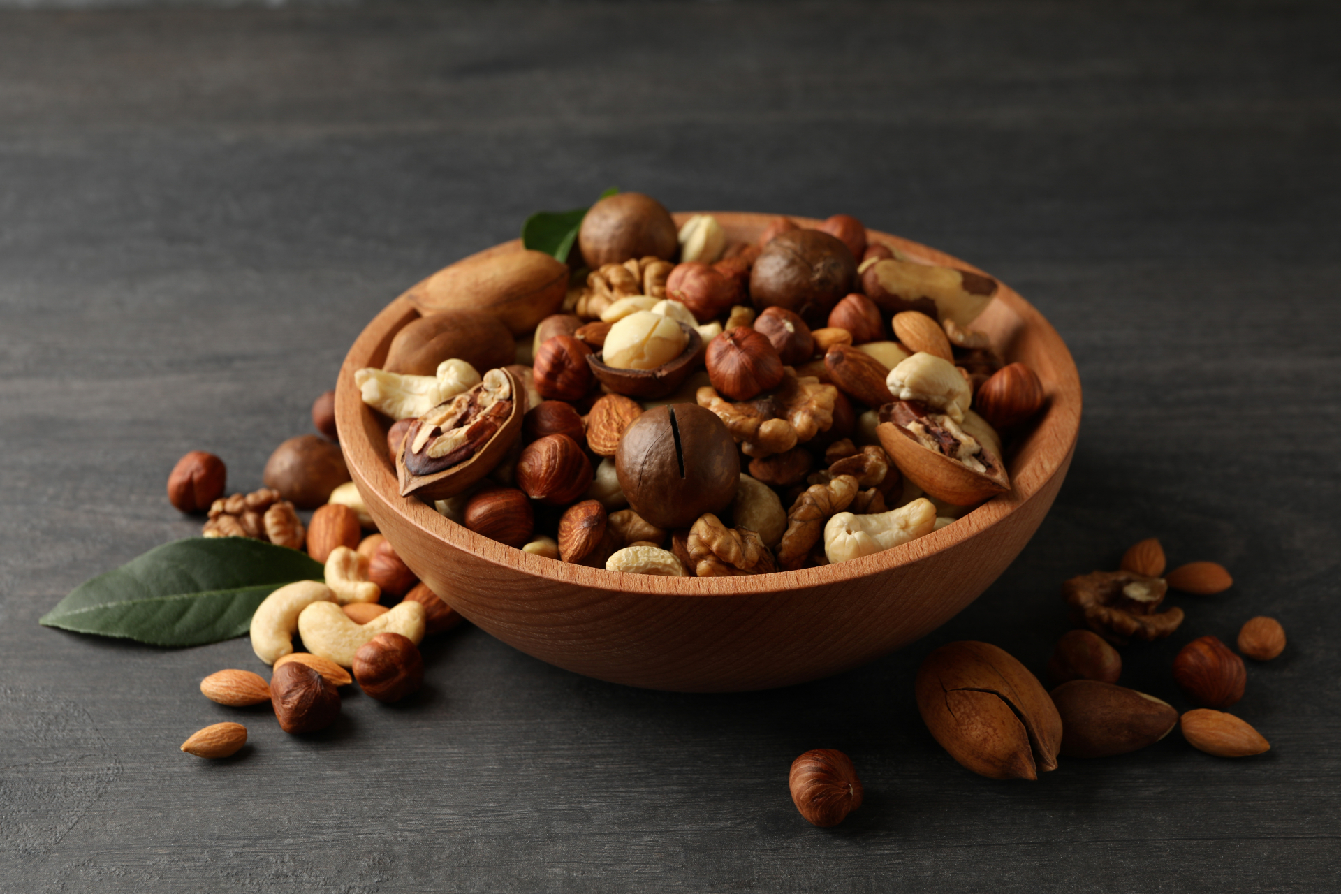 Wood,Bowl,With,Different,Tasty,Nuts,On,Gray,Wooden,Background